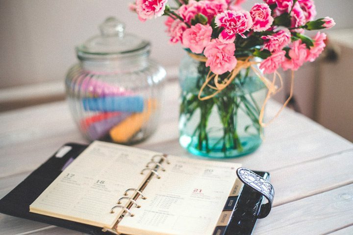 daily planner open on table near vase of pink flowers - #14days