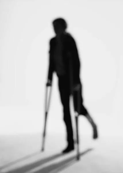 silhouette of person on crutches