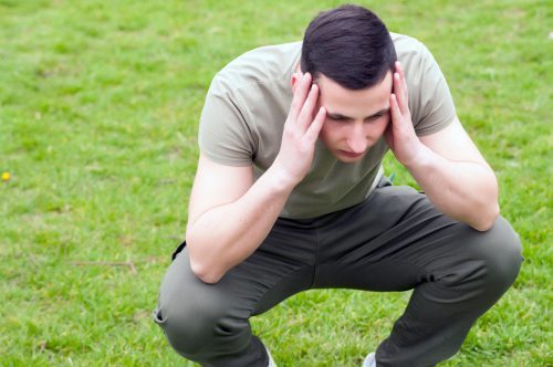 stressed man squatting with hands on head