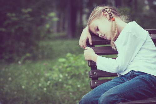 sad little girl alone on bench outside