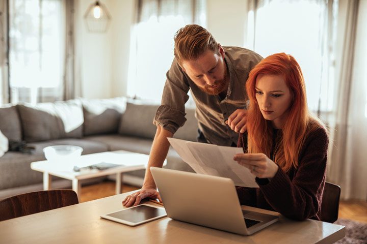 couple looking over papers and computer