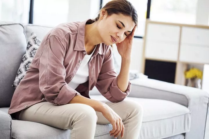 young woman on couch not feeling well