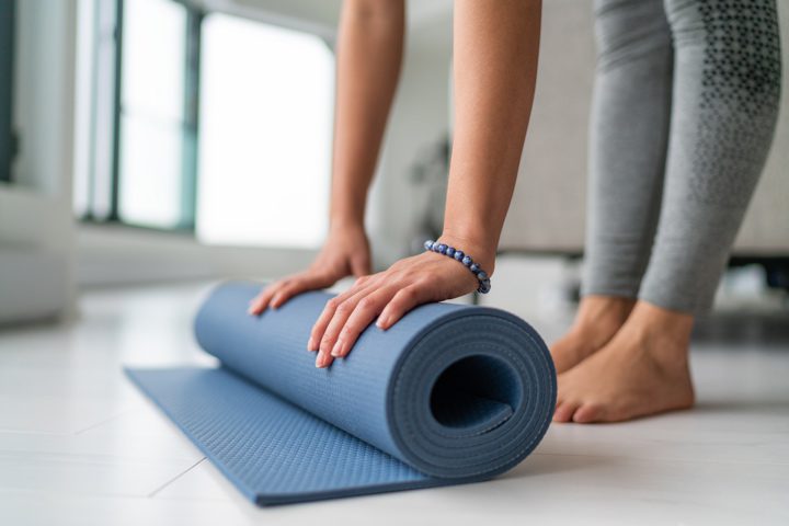 woman rolling up yoga mat - yoga teacher