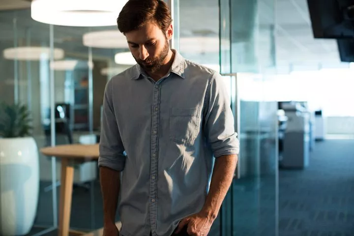 attractive young man at office looking depressed - causes of depression
