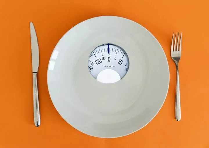plate that is also scales as place setting on an orange table - anorexia nervosa