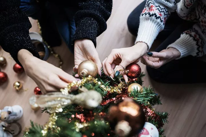 cropped shot of women's hands putting ornaments on a holiday tree - drama-free holiday season