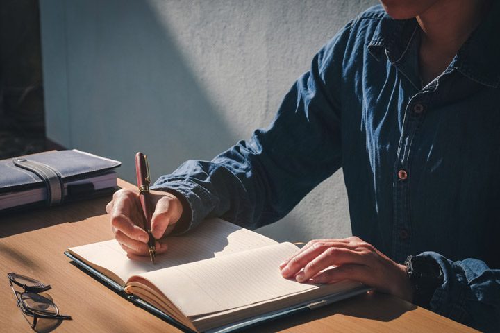man writing in journal - journaling