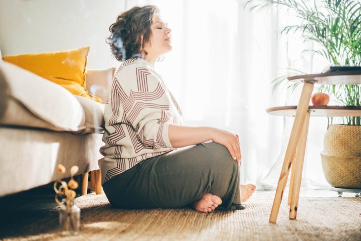 pretty young woman sitting cross-legged at home - meditation practice