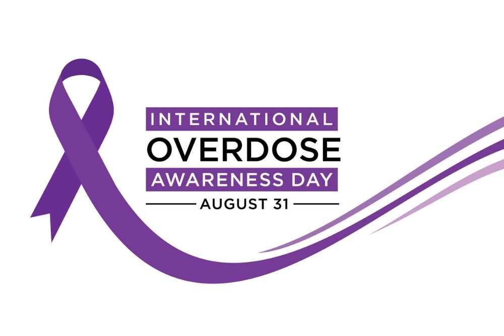 Graphic design for International Overdose Awareness Day on August 31, featuring a purple ribbon and flowing purple lines on a white background.